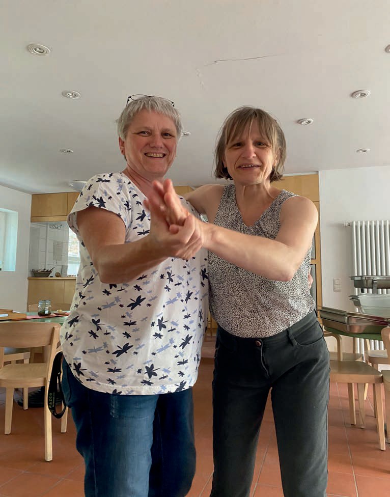 Zwei Frauen tanzen fröhlich miteinander in der Cafeteria.