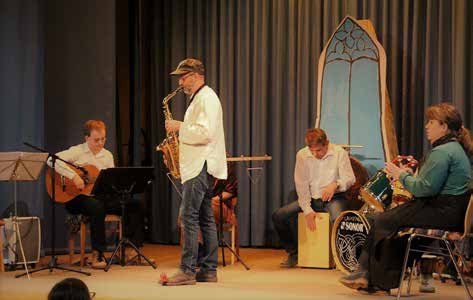 Auftritt in der Festhalle: ein Mann spielt Saxophon, um ihn herum Gitarre, Cajón und Schlagzeug.