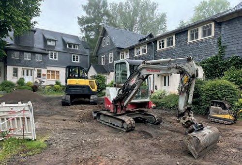 Vorher: Bagger auf aufgewühlter Erde vor den Häusern mit Schieferfassaden.