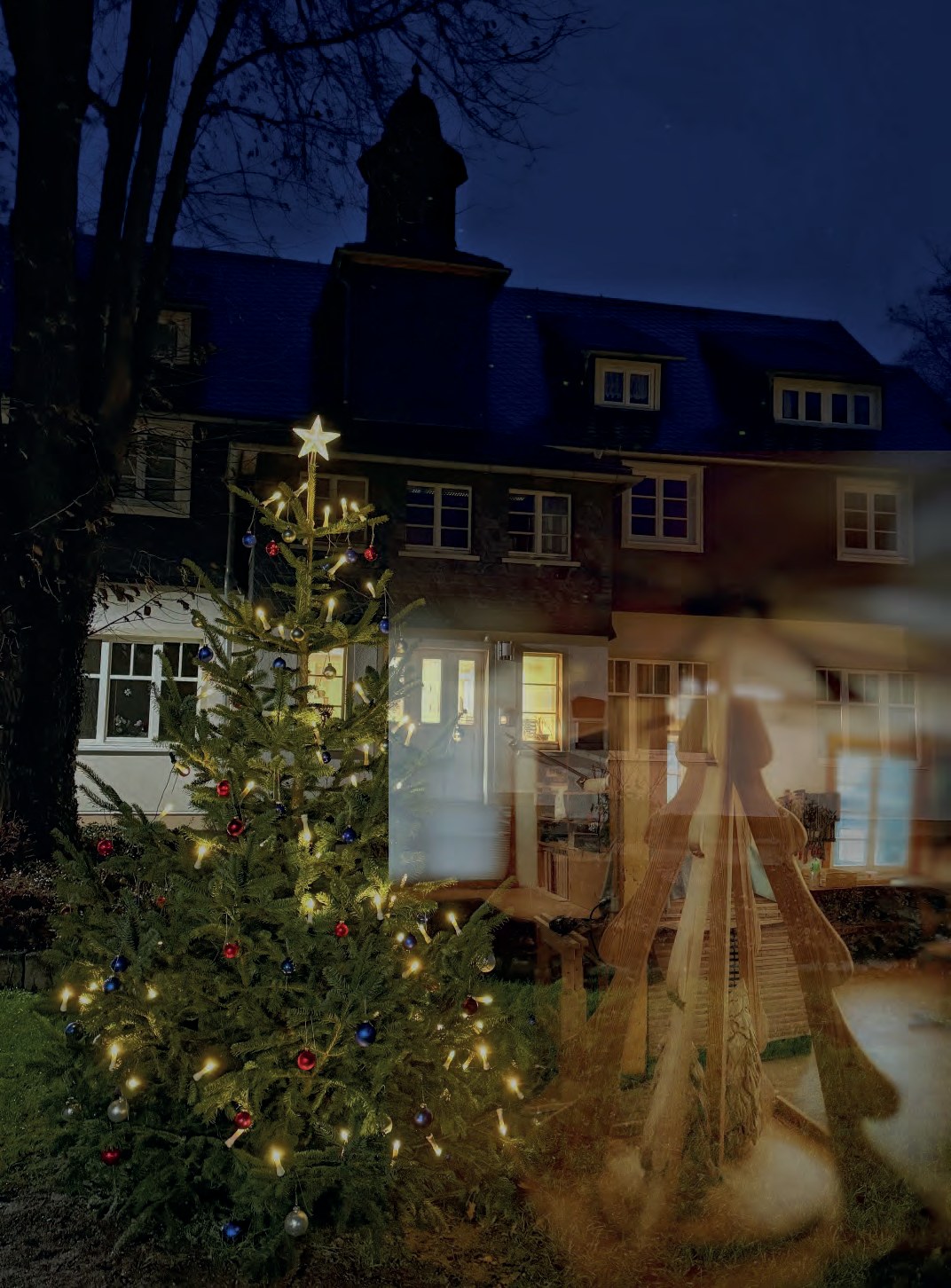 Fotomontage am Abend: der leuchtende Weihnachtsbaum vor dem Haus, daneben schimmert durchscheinend eine hölzerne Weihnachtspyramide.