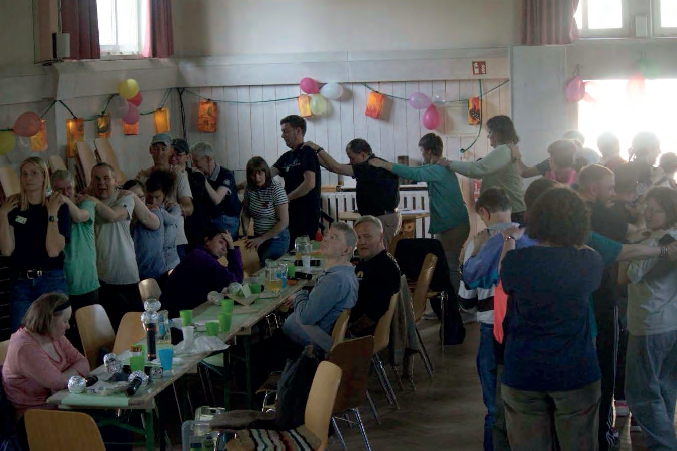 Eine lange Polonäse zieht durch die mit bunten Luftballons und Lampions geschmückte Festhalle, an den Tischen sitzen weitere Gäste.