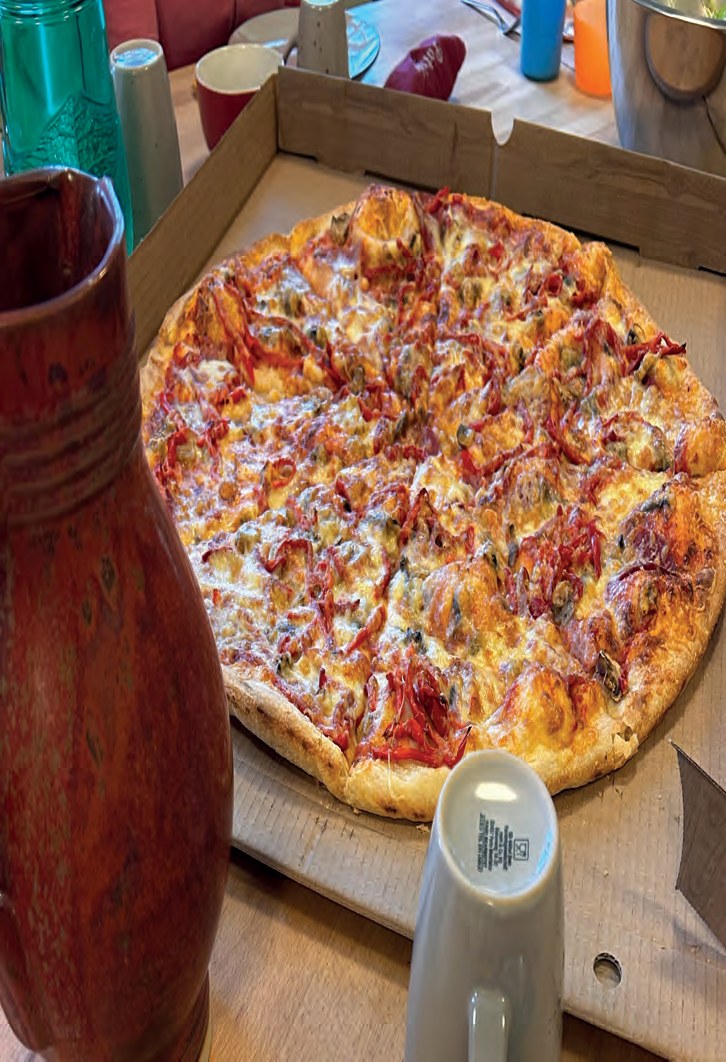 Eine sehr große Pizza mit Salami und Käse in einem aufgeklappten Pizzakarton.